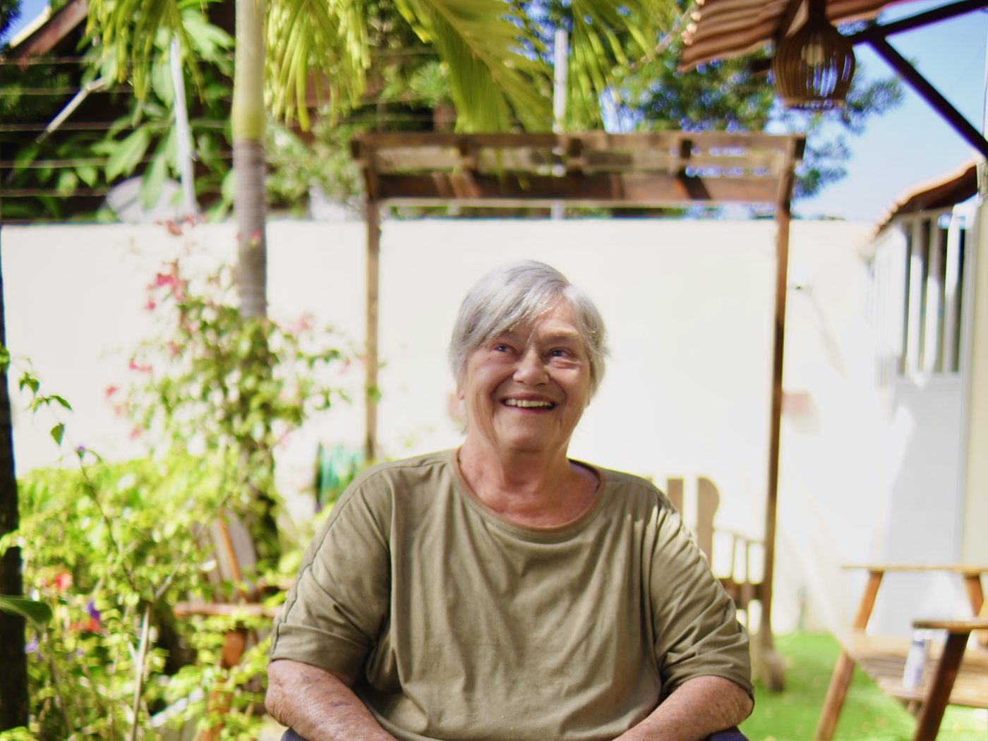 Moradora sorrindo no jardim da Villa